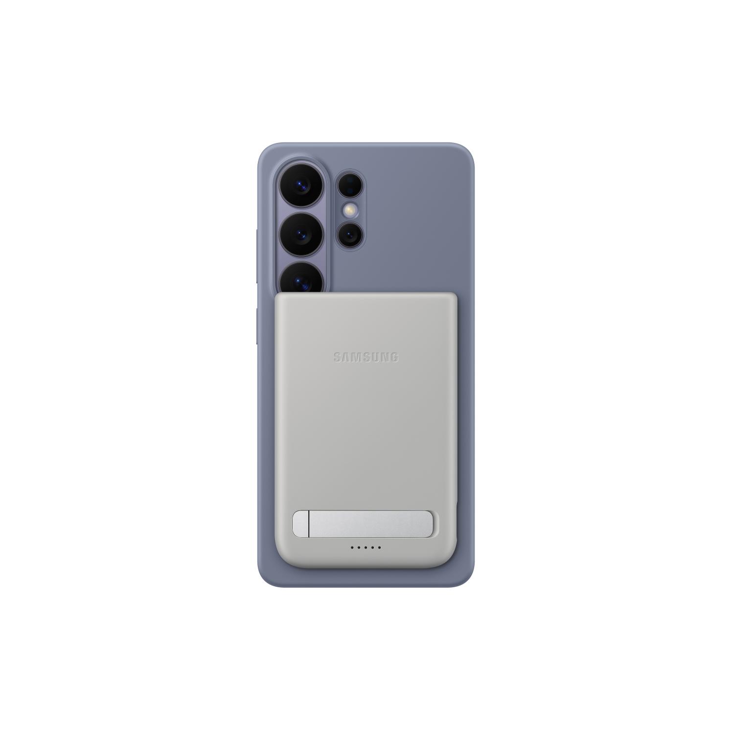Grey Samsung 5000mAh Qi2 magnetic power bank attached to the back of a smartphone with the folded stand and battery indicators visible