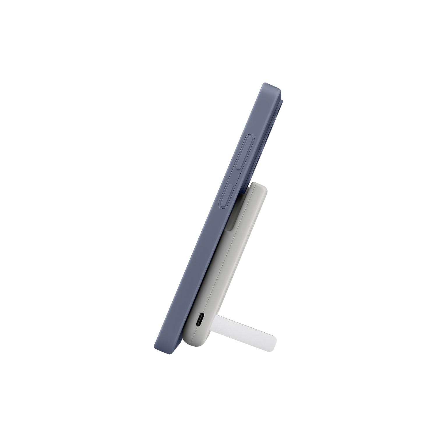 Side view of a smartphone held upright by the grey Samsung Qi2 magnetic power bank with its kickstand open