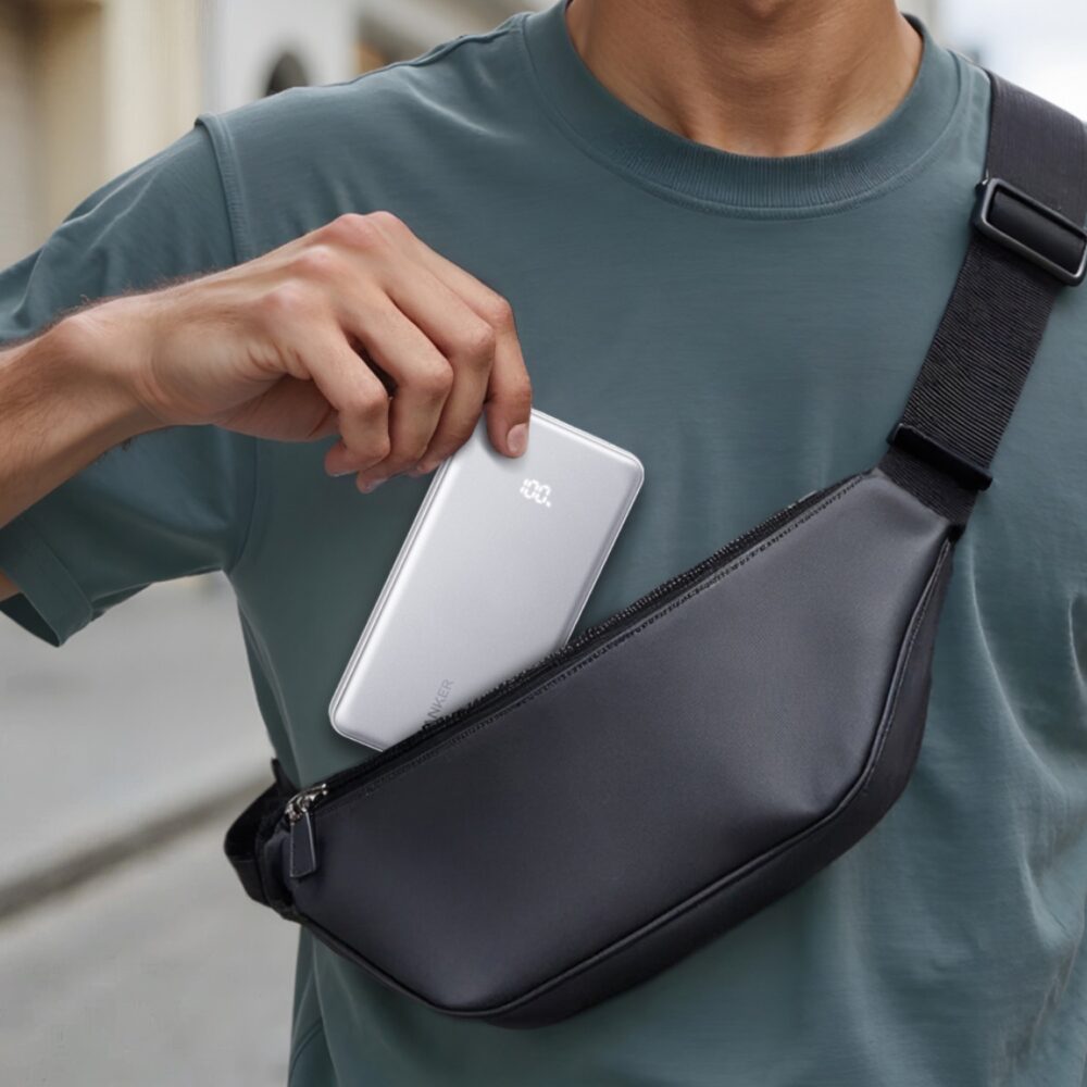 Person sliding the white Anker Zolo 10000mAh 22.5W power bank into a black crossbody bag.